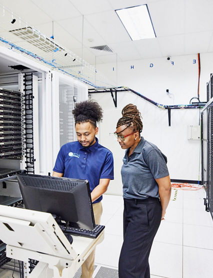 Medium wide shot of IT professionals in discussion while configuring server in data center