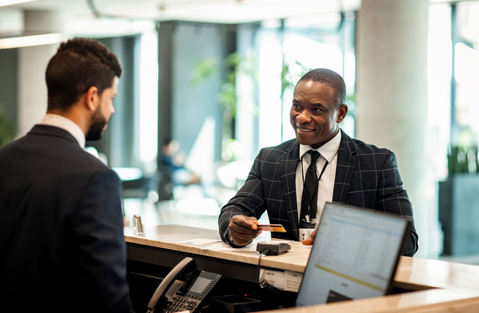 Businessman paying stay at hotel with credit card at reception