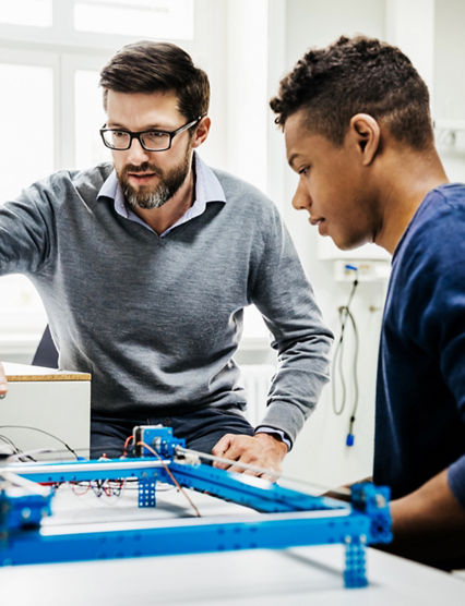 An engineering tutor assisting one of his students with a technical problem during teaching session at university.