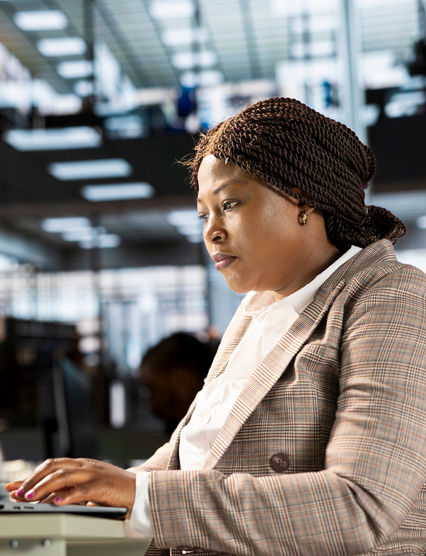 Skilled female investor working on financial forecasts at her workstation, using monthly infographics data to manage business tasks for enterprise development. Company progresses toward its goals.