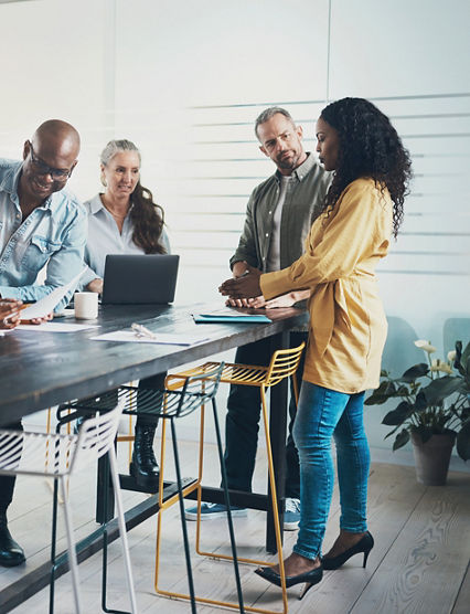 Smiling group of diverse businesspeople talking while working together around a table in a bright modern office