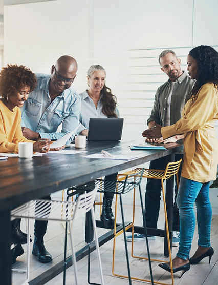 Smiling group of diverse businesspeople talking while working together around a table in a bright modern office