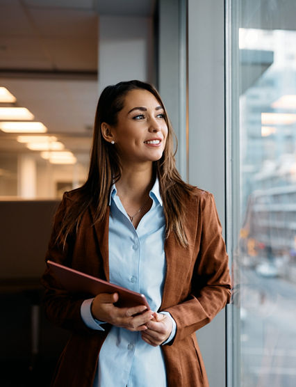 Pensive businesswoman with touchpad looking through window while working in office.