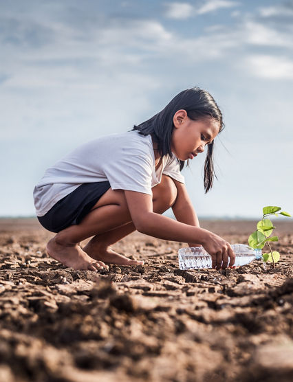 Asian girl watering green plant in dry land,Crack dried soil in drought and ,Climate change from global warming.