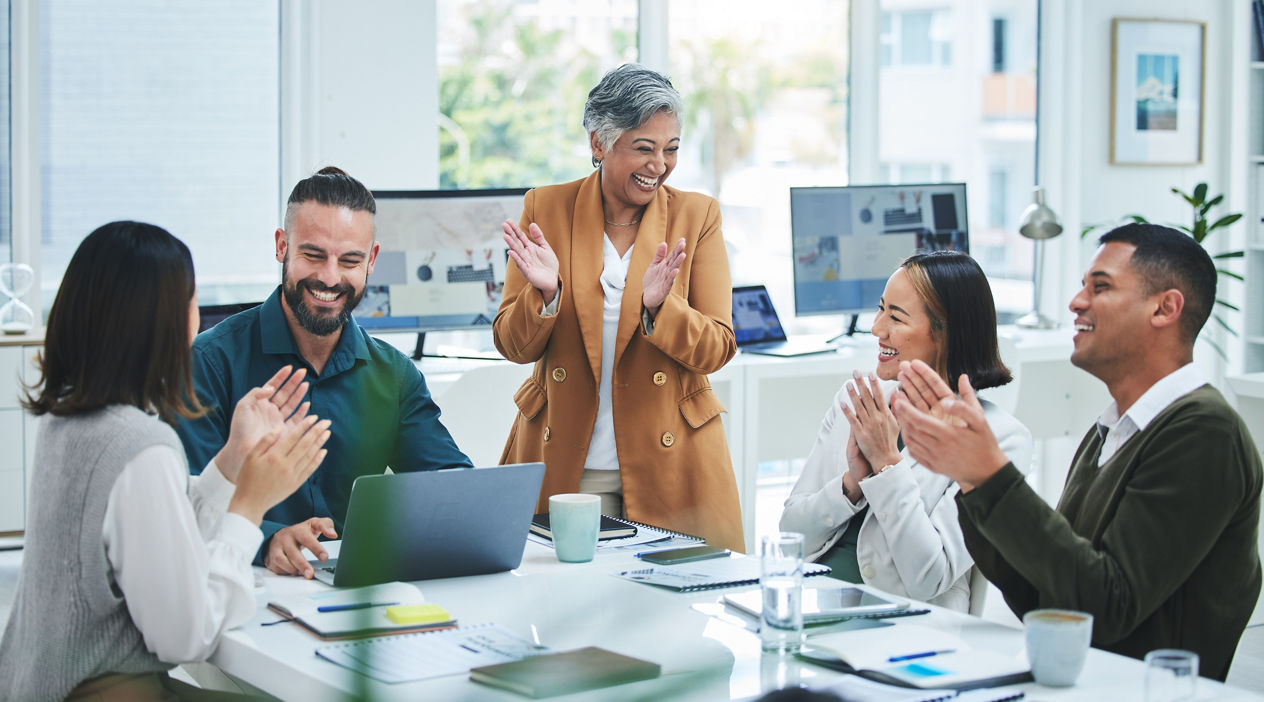Happy business people in meeting at desk with applause, cheers and celebration of sales target achievement. Clapping, praise and congratulations with success, motivation for men and women in office