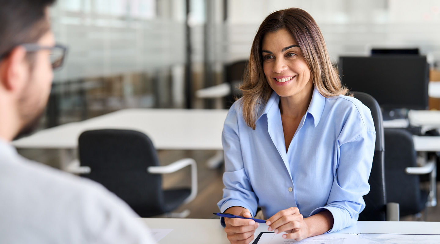 Smiling professional female hr having job interview meeting with male recruit. Happy middle aged business woman financial advisor, bank manager consulting client working in corporate office.