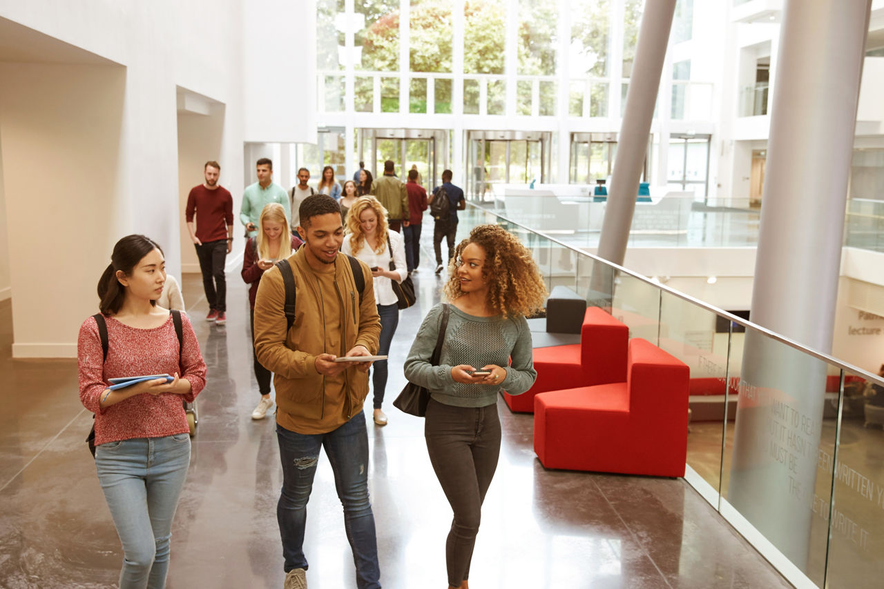 Students walk and talk using mobile devices in university