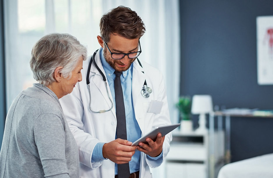 Shot of a doctor discussing something on a digital tablet with a senior patient in a clinic