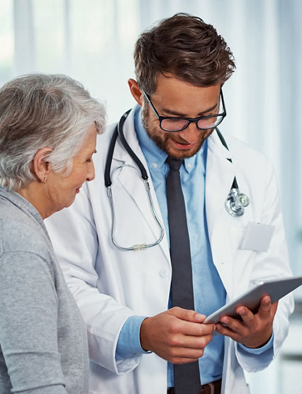 Shot of a doctor discussing something on a digital tablet with a senior patient in a clinic
