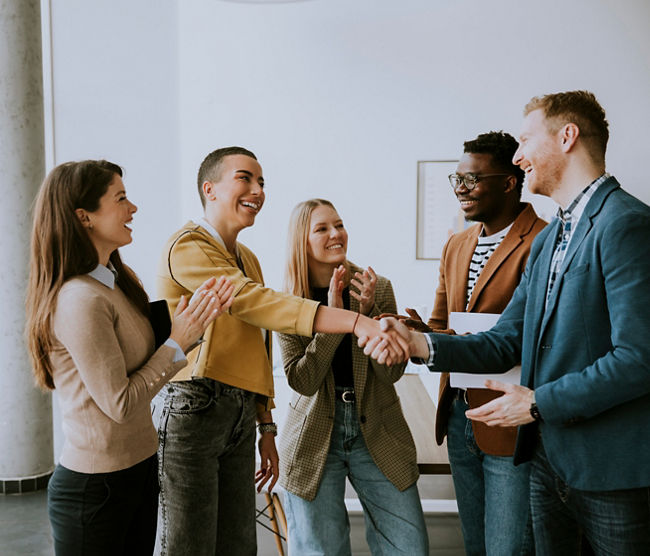 Memembers of young creative team shaking hands while working in the modern office