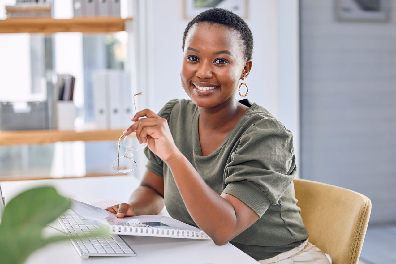 The key to success starts with how you define it. Portrait of an african businesswoman smiling while sitting at her desk.