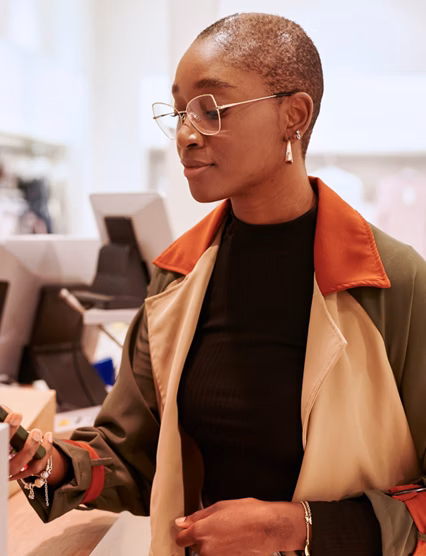 Smiling young woman paying for a purchase in a department store using her smartphone and nfc technology
