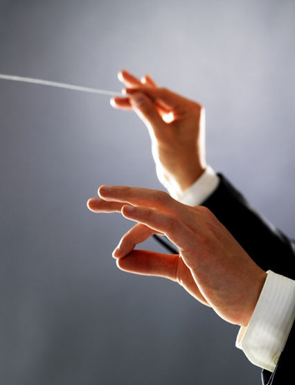 Cropped image of a male orchestra conductor directing with his baton in concert