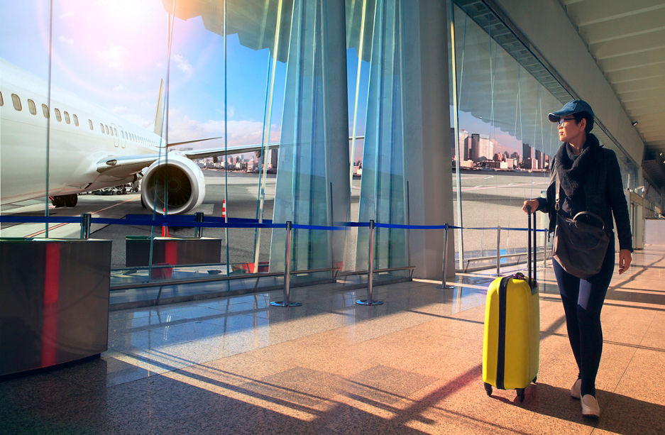 traveling woman and luggage walking in airport terminal and air plane flying outside