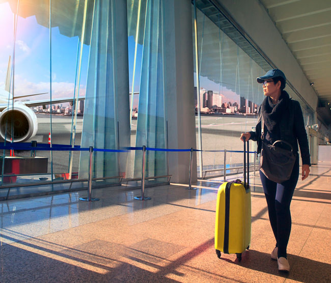 traveling woman and luggage walking in airport terminal and air plane flying outside