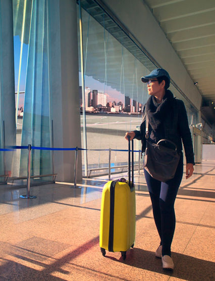 traveling woman and luggage walking in airport terminal and air plane flying outside