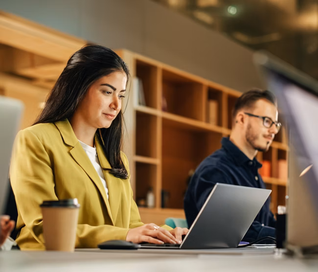 Group of Diverse Creative Team Members Using Laptops in an active Contemporary Office. Young Female Media Relations Manager Working on Brand Innovation Strategy and Collaborating with Colleagues.