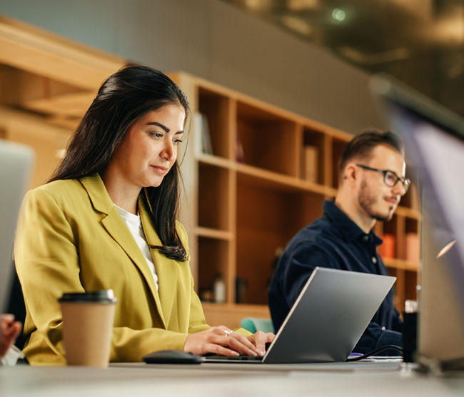 Group of Diverse Creative Team Members Using Laptops in an active Contemporary Office. Young Female Media Relations Manager Working on Brand Innovation Strategy and Collaborating with Colleagues.