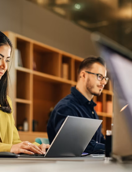 Group of Diverse Creative Team Members Using Laptops in an active Contemporary Office. Young Female Media Relations Manager Working on Brand Innovation Strategy and Collaborating with Colleagues.