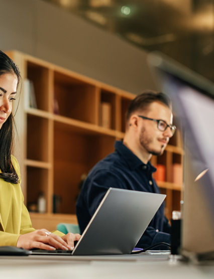 Group of Diverse Creative Team Members Using Laptops in an active Contemporary Office. Young Female Media Relations Manager Working on Brand Innovation Strategy and Collaborating with Colleagues.
