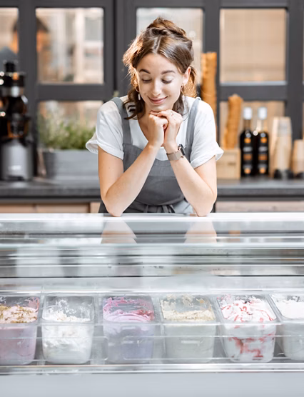 Portrait of a young and happy saleswoman at the counter in ice cream shop or cafe. Concept of a small business and retail