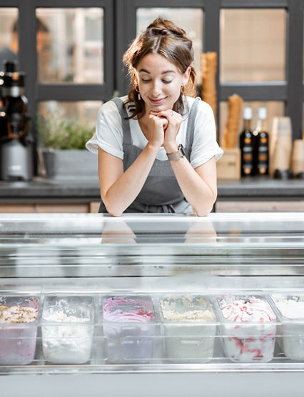 Portrait of a young and happy saleswoman at the counter in ice cream shop or cafe. Concept of a small business and retail