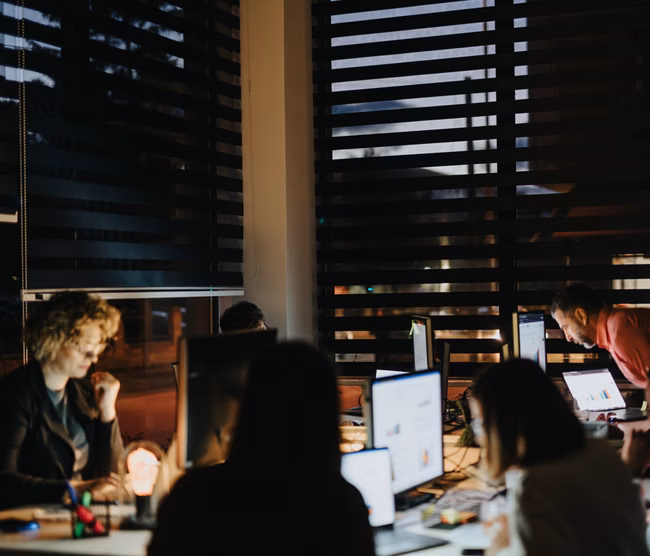 Late night collaboration in a creative office. Analyzing reports, strategizing for business growth. Multiracial team achieving achievements through teamwork.