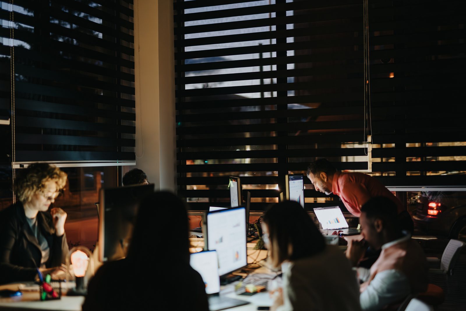 Late night collaboration in a creative office. Analyzing reports, strategizing for business growth. Multiracial team achieving achievements through teamwork.