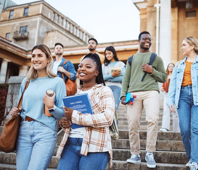 Diversity, students and walking on university steps, school stairs or college campus to morning class. Smile, happy people and bonding education friends in global scholarship opportunity or open day.