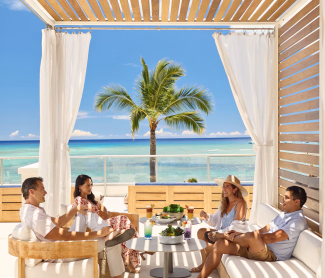 Group of people sitting outside near the beach at an Outrigger property