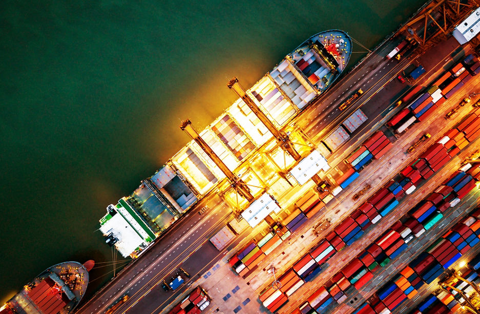 Top view of international port with Crane loading containers in import export business logistics at night.
