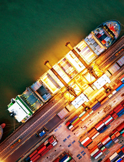 Top view of international port with Crane loading containers in import export business logistics at night.