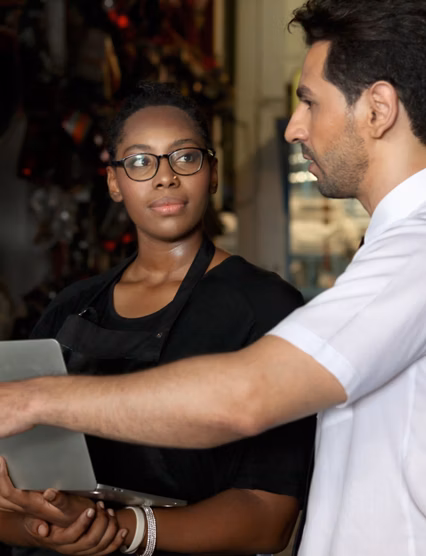 Happy harmony people at workplace, smiling white guy and African American woman working together Two workers check stock at auto spare parts store shop warehouse, surrounded by secondhand engine parts