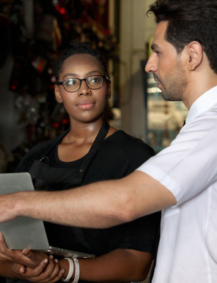 Happy harmony people at workplace, smiling white guy and African American woman working together Two workers check stock at auto spare parts store shop warehouse, surrounded by secondhand engine parts