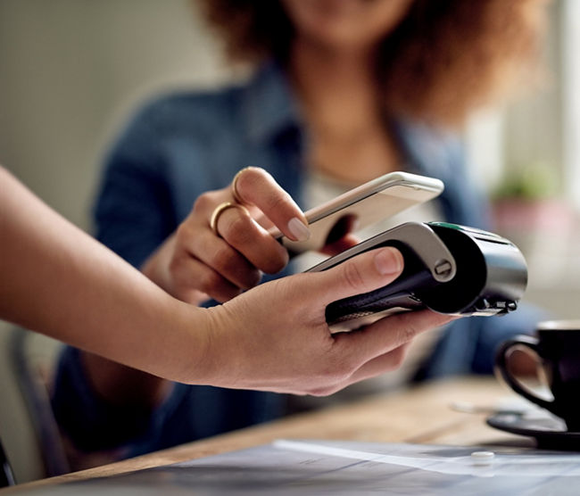 Closeup shot of a woman paying using NFC technology in a cafe