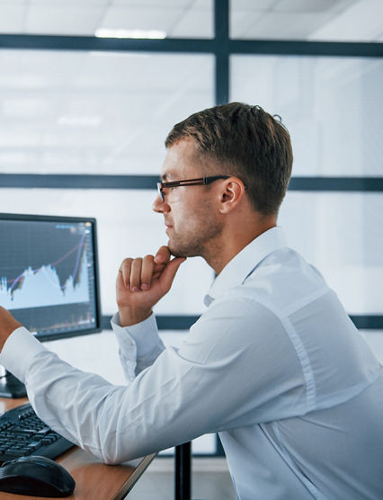 Analysing graphs. Young businessman in formal clothes is in office with multiple screens. Conception of exchange and money.