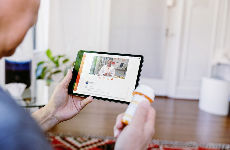 While holding a prescription medication container, an unrecognizable senior man video chats with a female doctor. The man is asking quesitons about his medication.