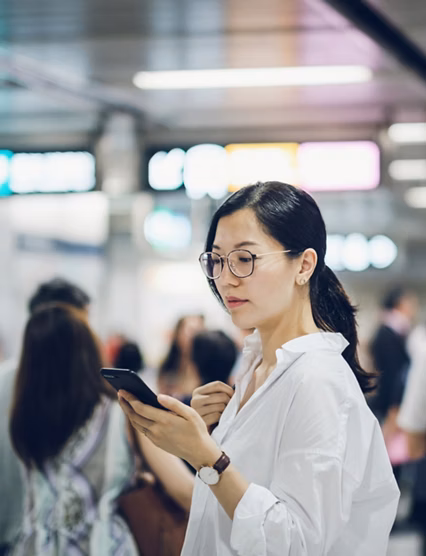 Beautiful young woman using smartphone in subway station during rush hour