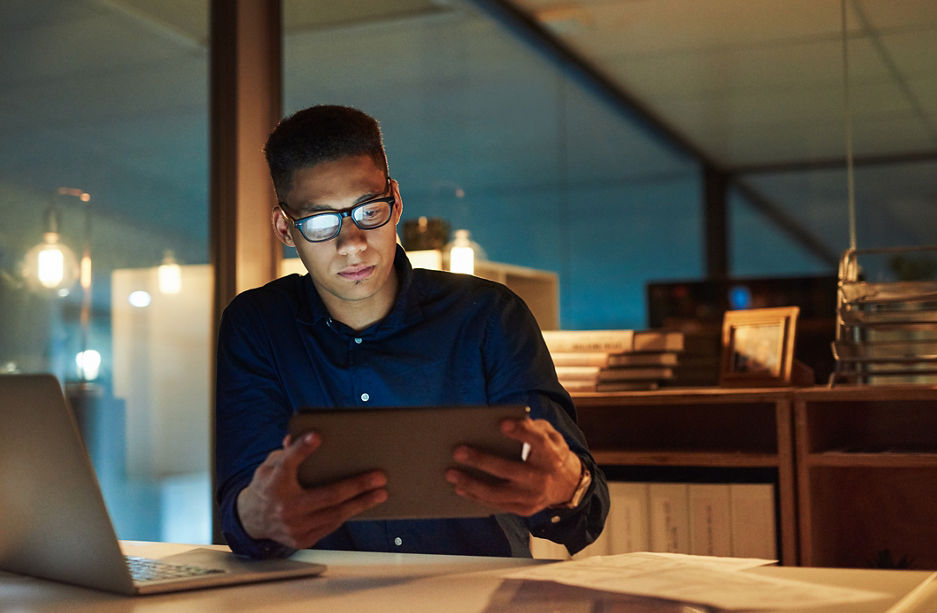 Shot of a young businessman using a digital tablet during a late night at work