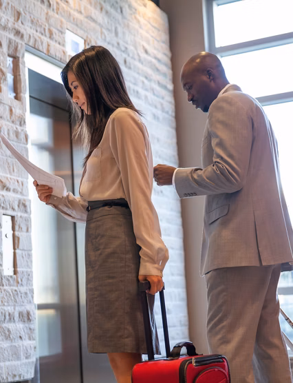 Business people with luggage using hotel elevator