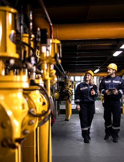 Industrial workers controlling production of natural gas and distribution in refinery.