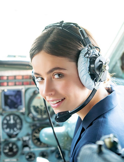 Happy and successful flight. Smiling female pilot in the aircraft , she is holding aviator headset and looking at camera. Wishes a successful fligh