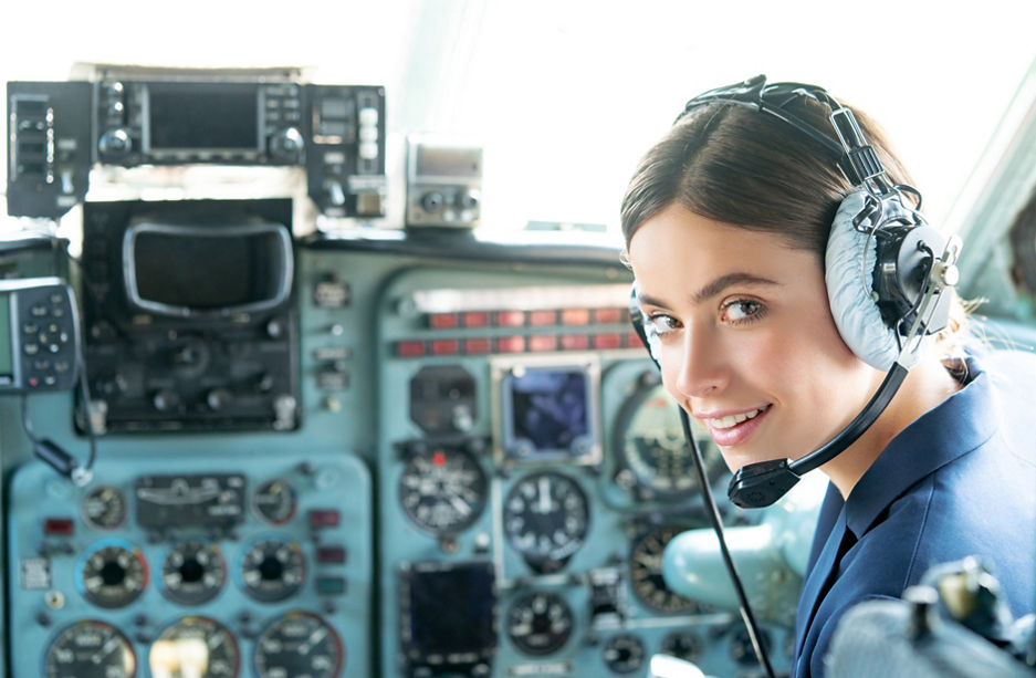 Happy and successful flight. Smiling female pilot in the aircraft , she is holding aviator headset and looking at camera. Wishes a successful fligh