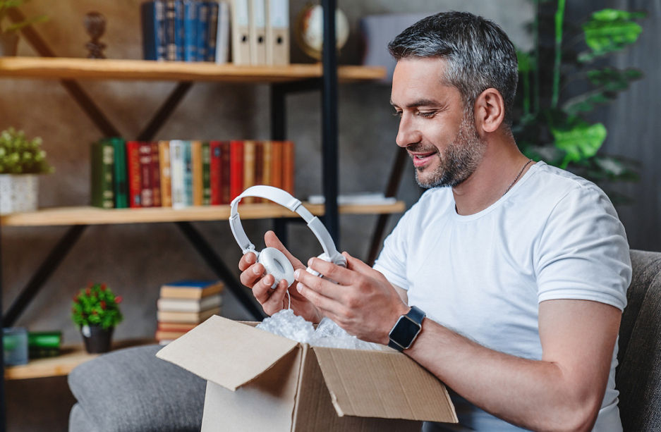 Joyful middle aged man get his delivery with heaphones at home
