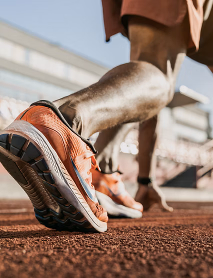 Close up of male athlete getting ready to start running on track . Focus on sneakers