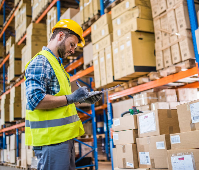 Male worker checking checklist in warehouse.