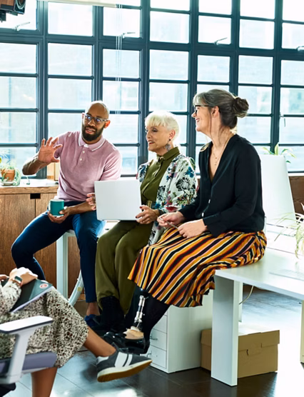 Diver group of mixed age and multi ethnic colleagues in discussion, mid adult man explaining and gesturing, woman with artificial limb smiling and listening