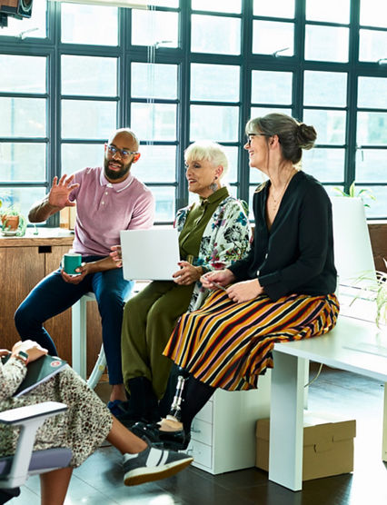 Diver group of mixed age and multi ethnic colleagues in discussion, mid adult man explaining and gesturing, woman with artificial limb smiling and listening