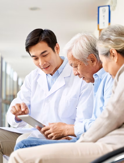 young asian doctor discussing test result and diagnosis with senior couple patients using digital tablet in hospital hallway