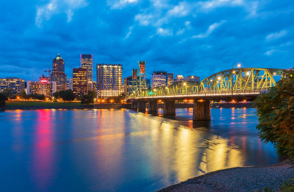Skyline of Portland, Oregon, USA at dusk, with Willamette River and Hawthorne Bridge.